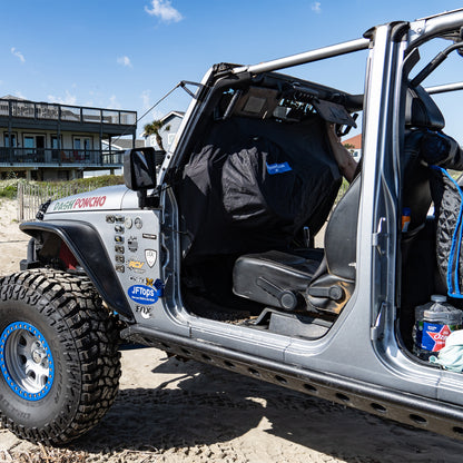 Open door of a silver off-road vehicle with JKU JEEP WRANGLER RAIN COVER on the Beach with  clear sky and building in the background